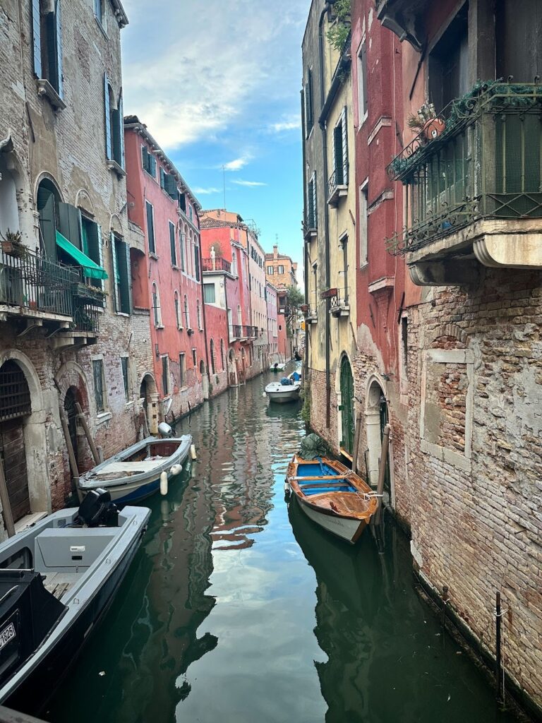 skinny canal in Venice, Italy with boats. Is Venice worth Visiting?